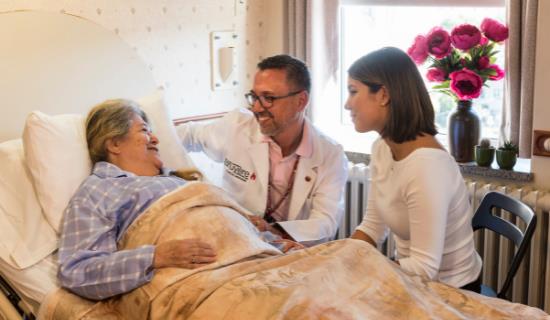 young woman and male doctor comfort elderly woman in bed