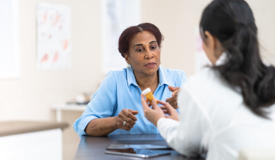 pharmacist shows medication bottle to woman