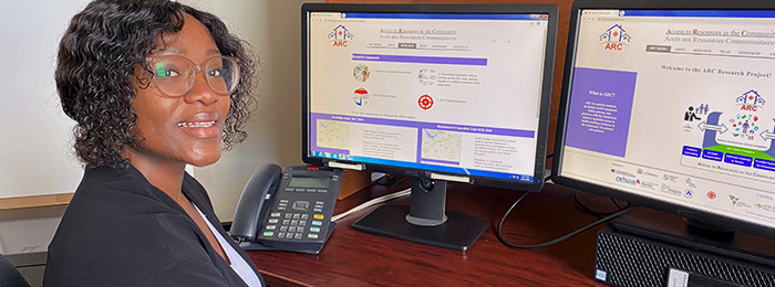 Natacha Ndihokubwayo sits at her desk with two screens