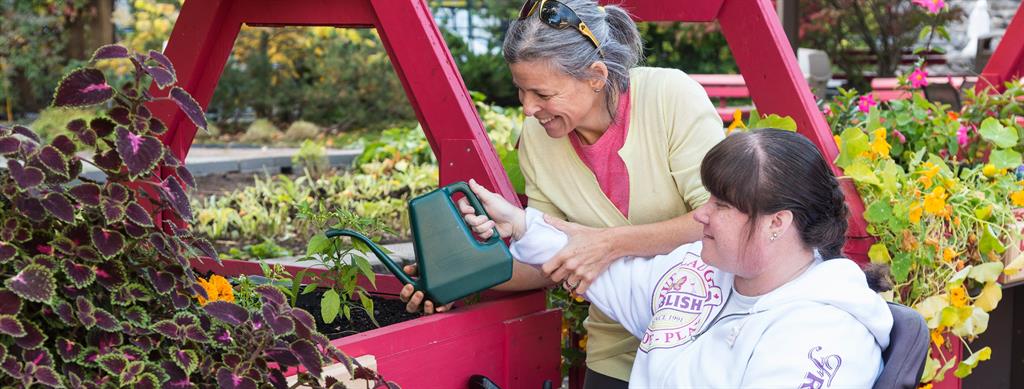 Two people watering garden and smiling